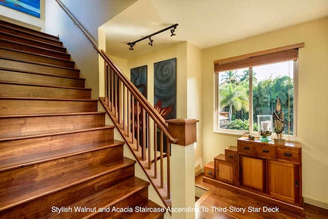 staircase with hardwood / wood-style floors and track lighting