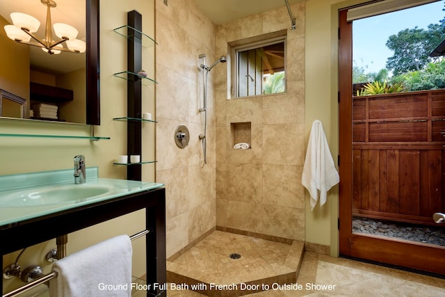 bathroom with tile patterned floors, a notable chandelier, a tile shower, and vanity