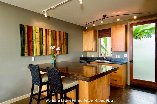 kitchen with a kitchen bar, kitchen peninsula, track lighting, sink, and light brown cabinets