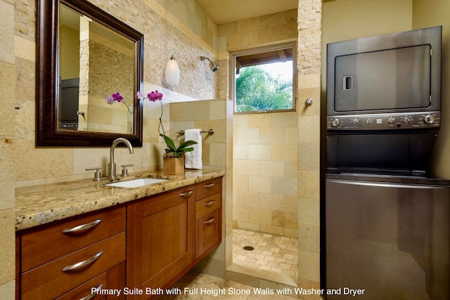 bathroom featuring a shower, vanity, and tile walls