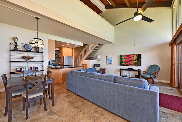 living room with beam ceiling, a towering ceiling, and ceiling fan