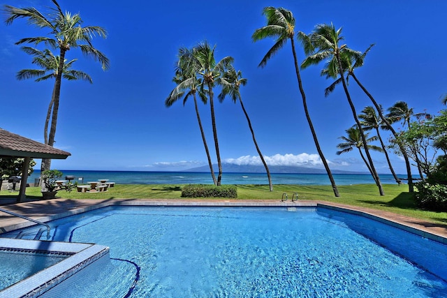 view of swimming pool with a lawn and a water view