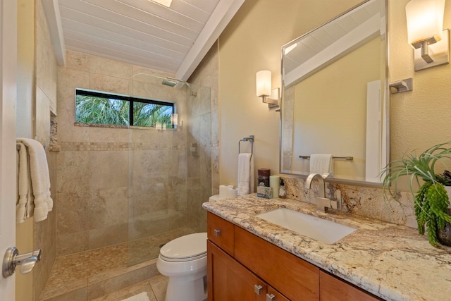 bathroom with toilet, tile patterned flooring, a tile shower, and vanity