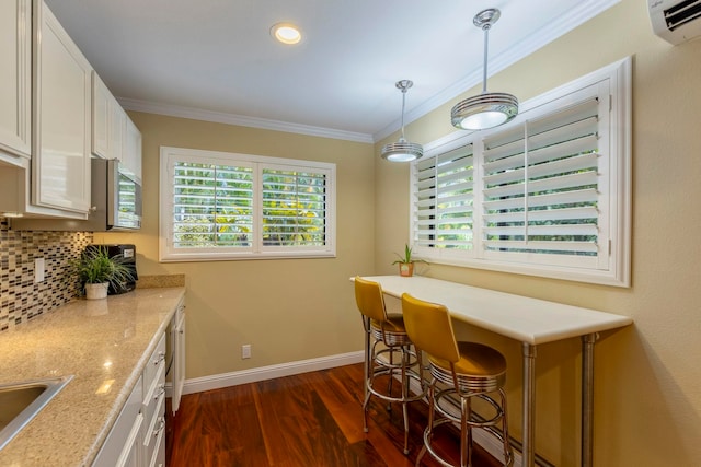 kitchen with light stone countertops, decorative light fixtures, tasteful backsplash, crown molding, and white cabinets