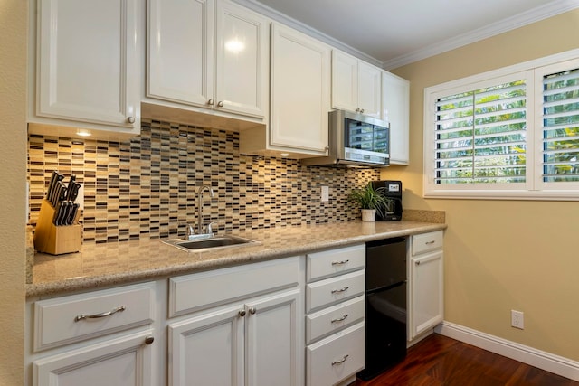 kitchen with sink, white cabinets, light stone counters, decorative backsplash, and crown molding