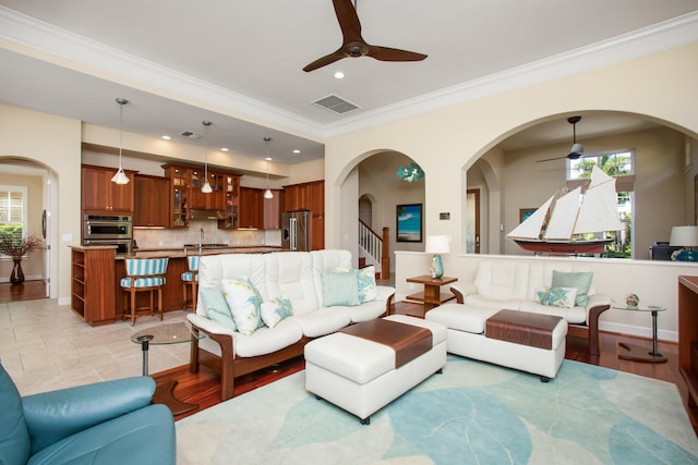 living room featuring visible vents, arched walkways, ceiling fan, ornamental molding, and recessed lighting