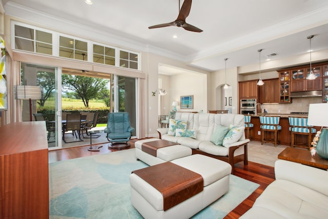 living area featuring ornamental molding, wood finished floors, visible vents, and a ceiling fan