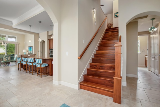 stairs featuring arched walkways, crown molding, and baseboards