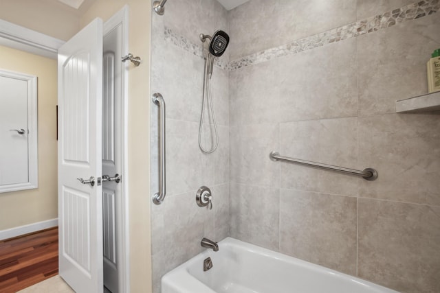 bathroom with washtub / shower combination, baseboards, and wood finished floors