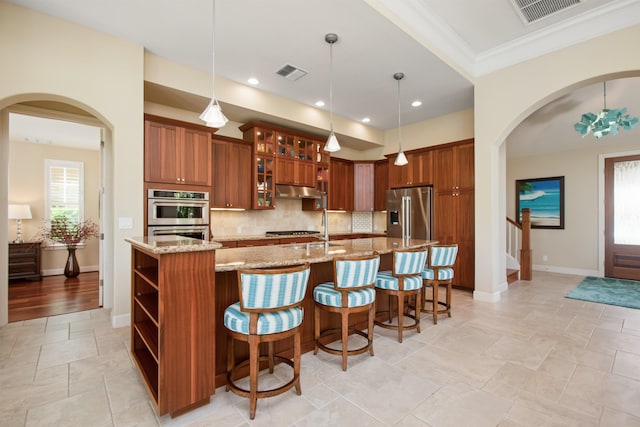 kitchen featuring stainless steel appliances, brown cabinets, visible vents, and decorative backsplash