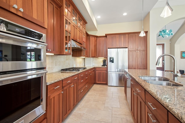 kitchen featuring brown cabinetry, appliances with stainless steel finishes, backsplash, and a sink