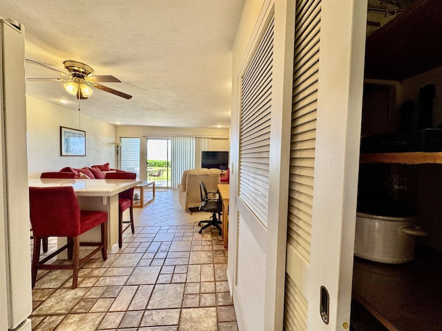 interior space featuring a textured ceiling, stone tile floors, and ceiling fan