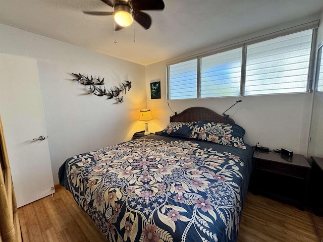 bedroom with multiple windows, wood finished floors, and a ceiling fan