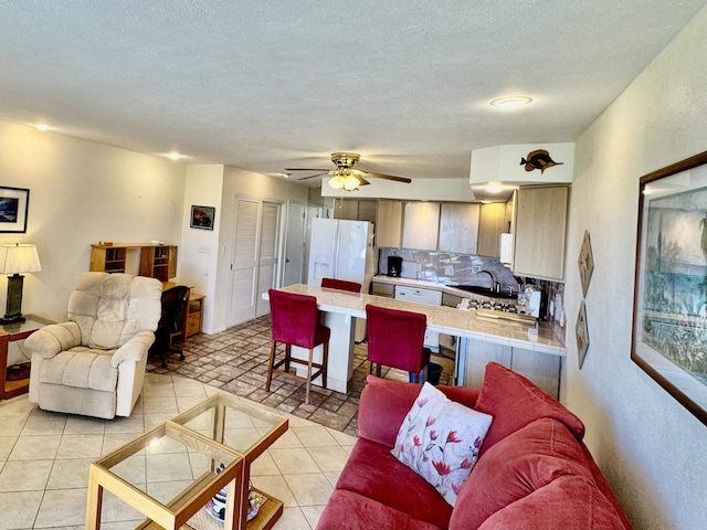 living room with light tile patterned floors, a textured ceiling, and ceiling fan