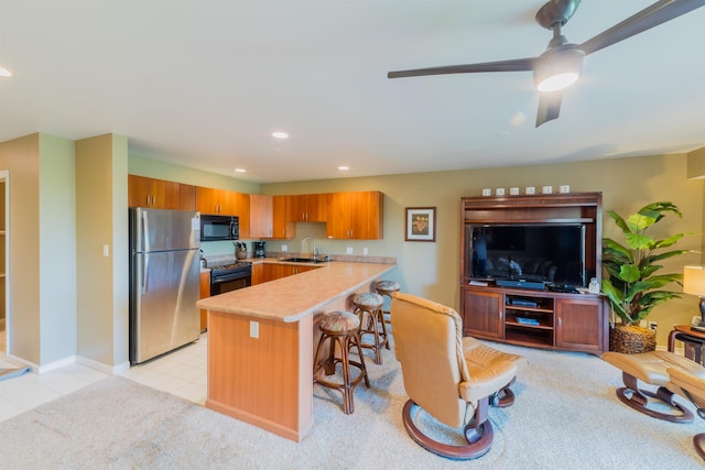 kitchen featuring a kitchen bar, kitchen peninsula, black appliances, ceiling fan, and sink