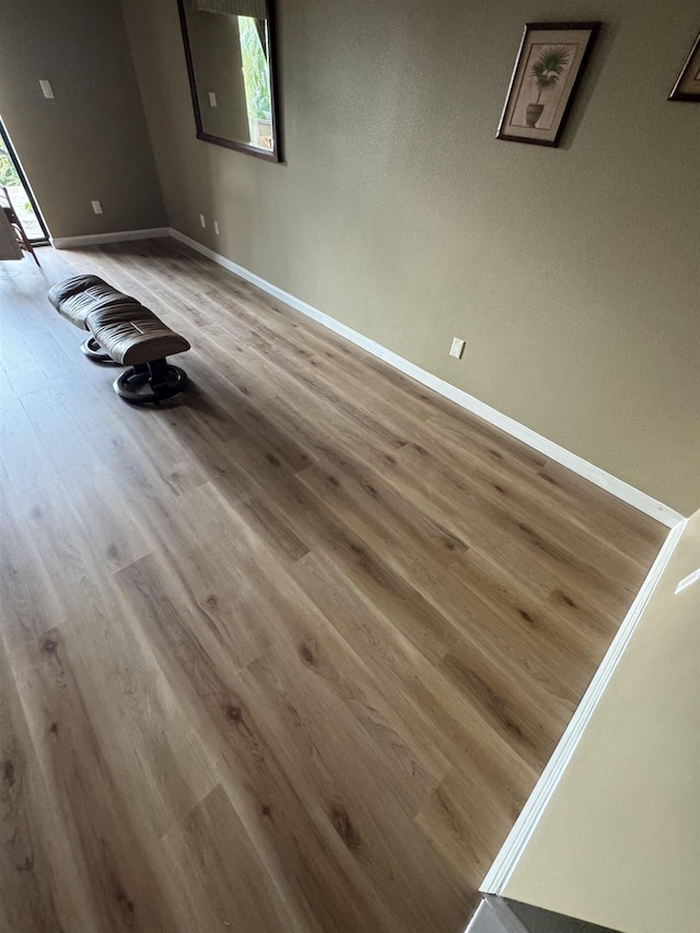 unfurnished room featuring baseboards, wood finished floors, and a healthy amount of sunlight