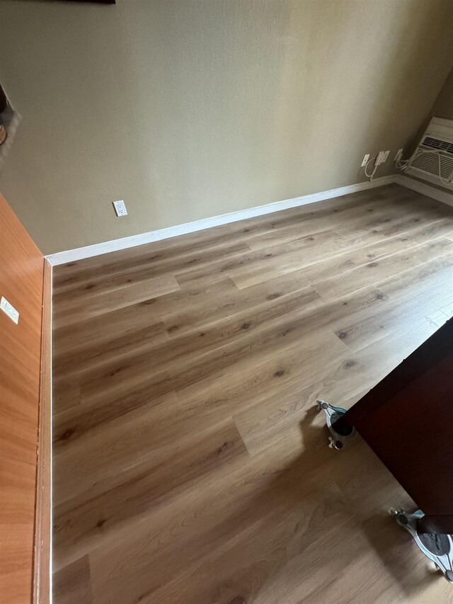 room details featuring wood finished floors, a wall unit AC, and baseboards