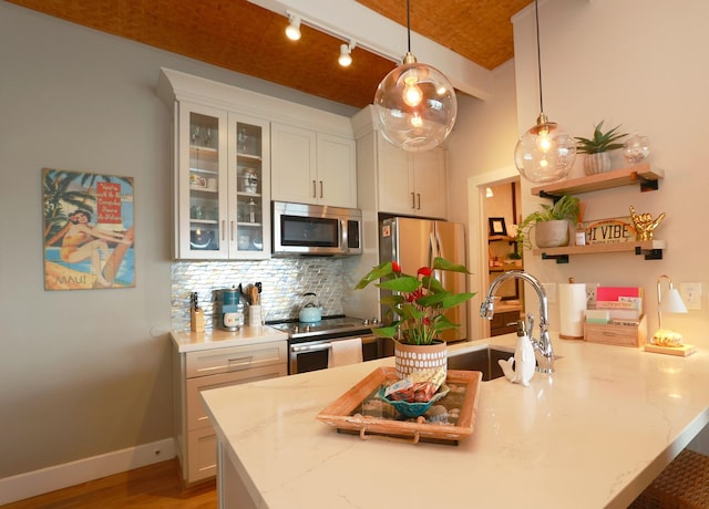 kitchen with pendant lighting, stainless steel appliances, light stone countertops, white cabinets, and decorative backsplash