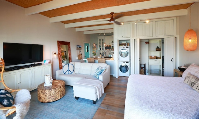 bedroom featuring stacked washing maching and dryer, dark hardwood / wood-style flooring, and beam ceiling