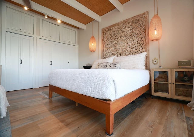 bedroom with wood-type flooring and beam ceiling