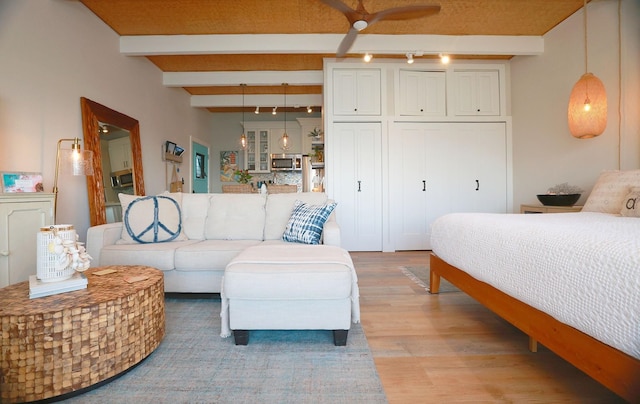 bedroom featuring beamed ceiling, rail lighting, and light wood-type flooring