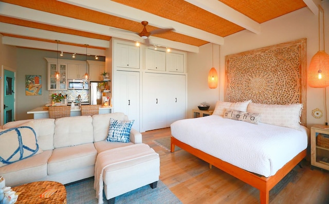 bedroom with wood-type flooring, beam ceiling, and a closet