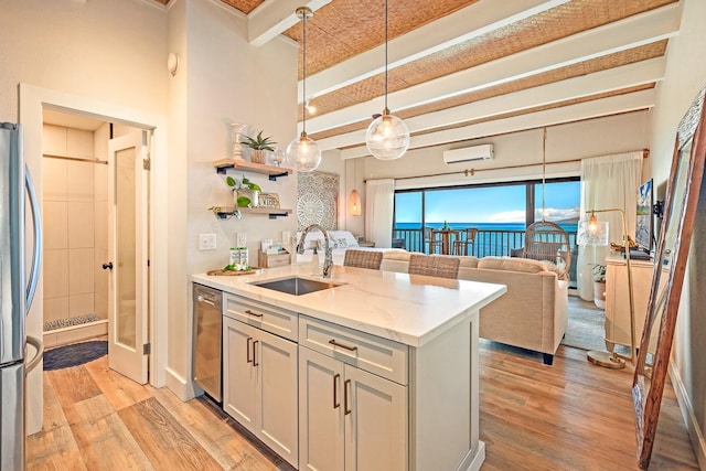 kitchen featuring pendant lighting, sink, stainless steel appliances, a wall mounted AC, and light stone counters