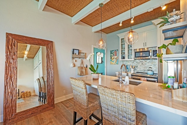 kitchen with decorative light fixtures, sink, a breakfast bar area, kitchen peninsula, and stainless steel appliances