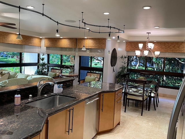 kitchen with dark stone countertops, hanging light fixtures, sink, and stainless steel dishwasher