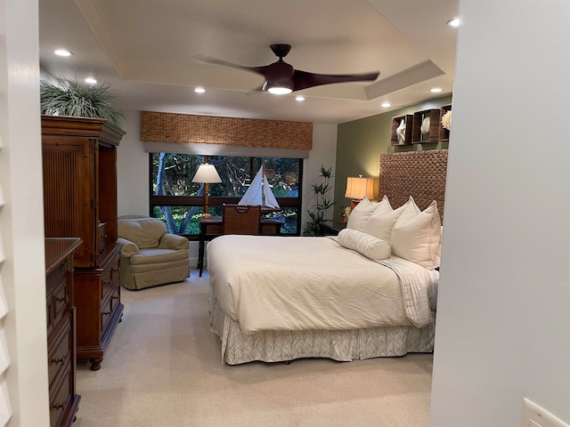 carpeted bedroom with ceiling fan and a tray ceiling