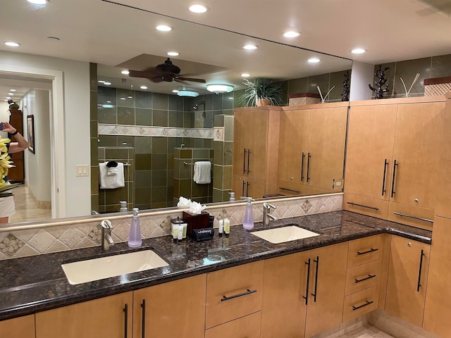 bathroom featuring ceiling fan, dual bowl vanity, and tasteful backsplash