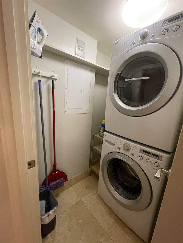 laundry area with stacked washer / dryer, electric panel, and light tile patterned floors