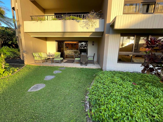 exterior space with a balcony, an outdoor living space, a patio, and a yard