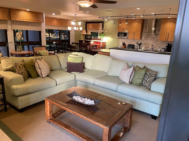 living room featuring ceiling fan with notable chandelier, track lighting, and carpet flooring