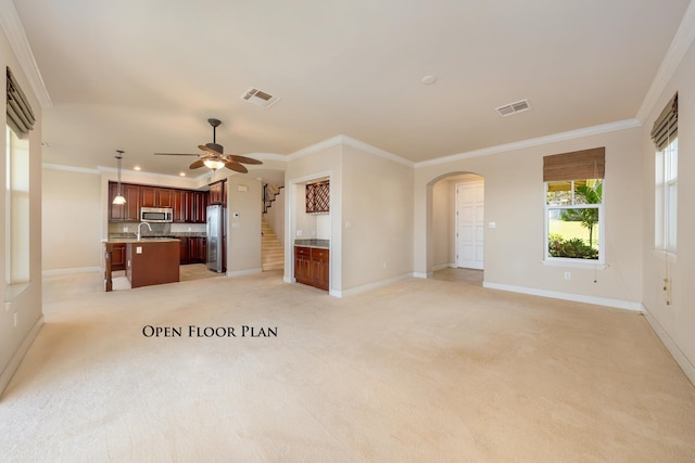 unfurnished living room with light carpet, ceiling fan, and ornamental molding