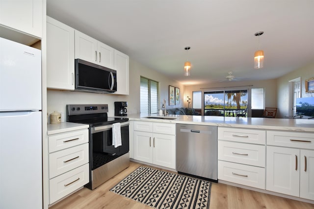 kitchen featuring a sink, appliances with stainless steel finishes, open floor plan, and plenty of natural light