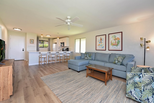 living room with a ceiling fan, light wood-style floors, and a healthy amount of sunlight