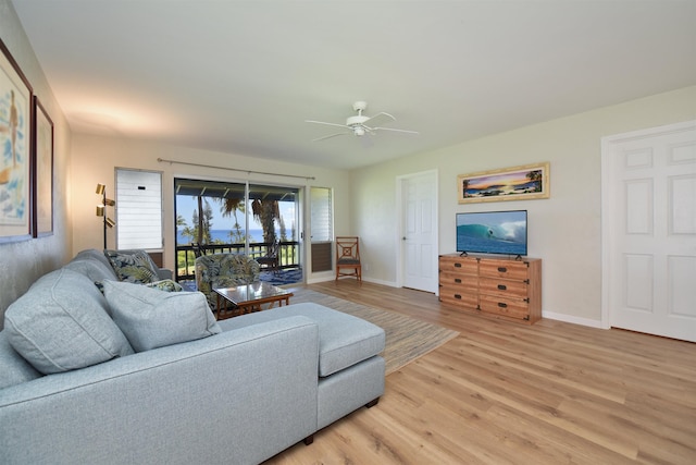 living area featuring a ceiling fan, light wood-style flooring, and baseboards