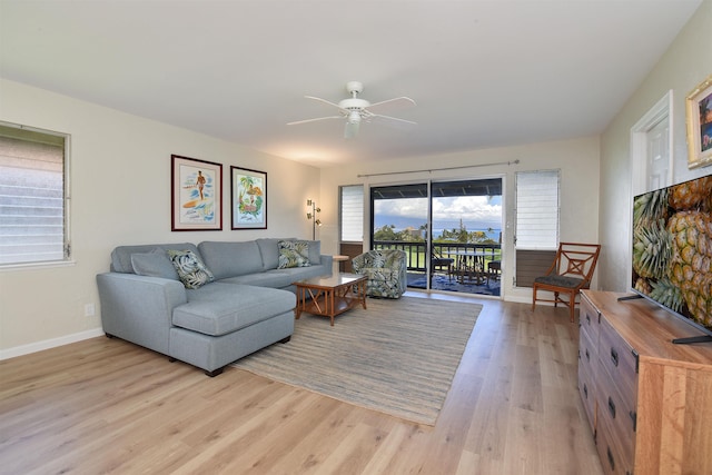 living area with a ceiling fan, light wood-style flooring, and baseboards