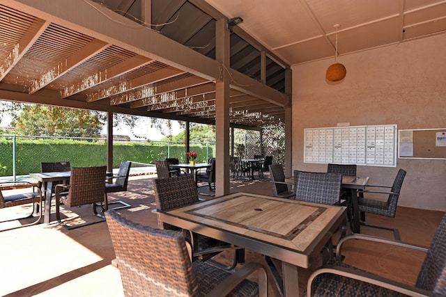 view of patio / terrace featuring fence, mail area, and outdoor dining area