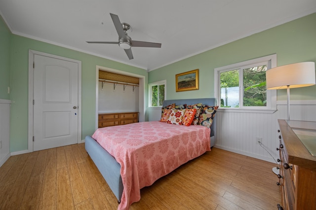 bedroom featuring light hardwood / wood-style floors, ornamental molding, a closet, and ceiling fan