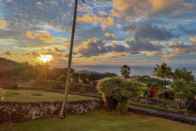 yard at dusk featuring a water view