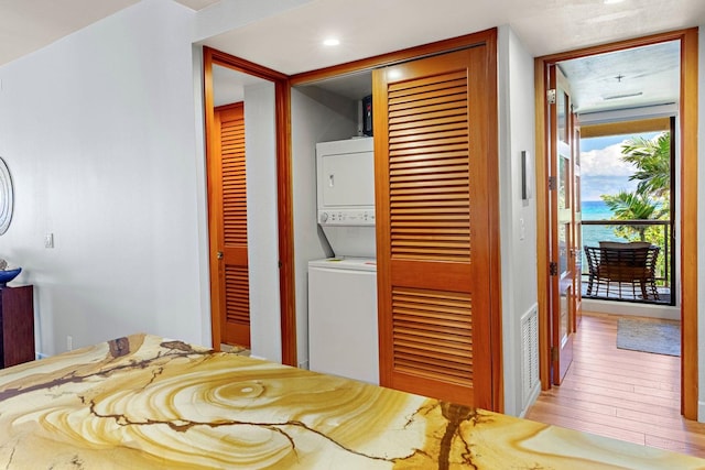 bedroom featuring stacked washer / dryer, access to outside, light hardwood / wood-style flooring, and a closet