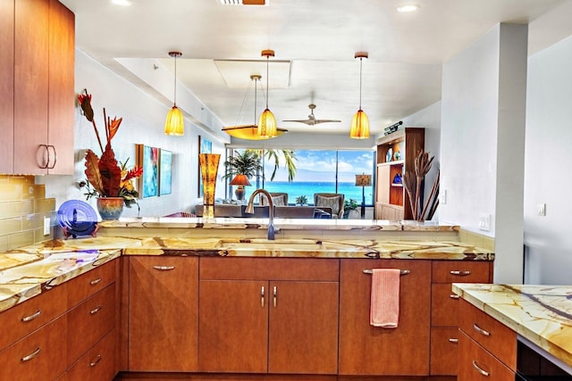 kitchen with pendant lighting, tasteful backsplash, a water view, and sink