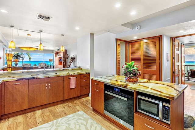 kitchen with appliances with stainless steel finishes, a wealth of natural light, sink, and light hardwood / wood-style flooring