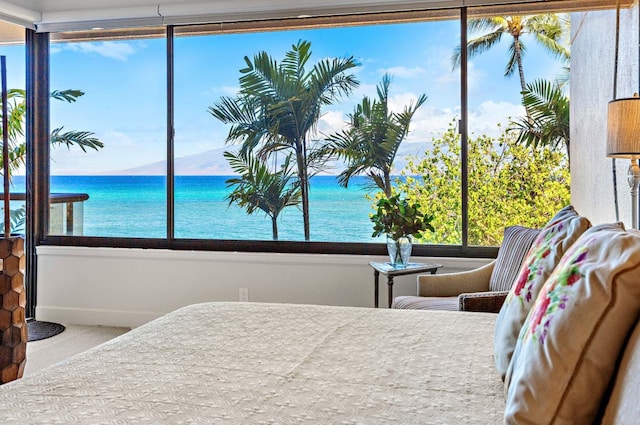 carpeted bedroom featuring a water view and multiple windows