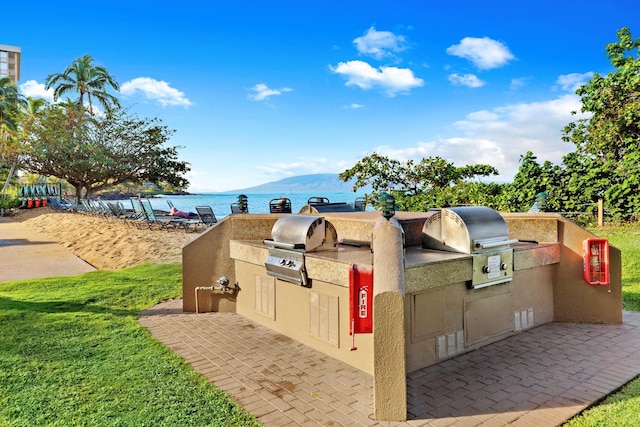 exterior space featuring exterior kitchen, a lawn, and a water and mountain view