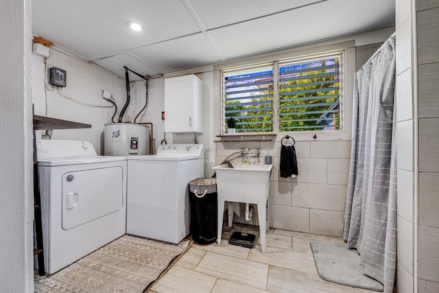 laundry room featuring electric water heater, washing machine and clothes dryer, and cabinet space