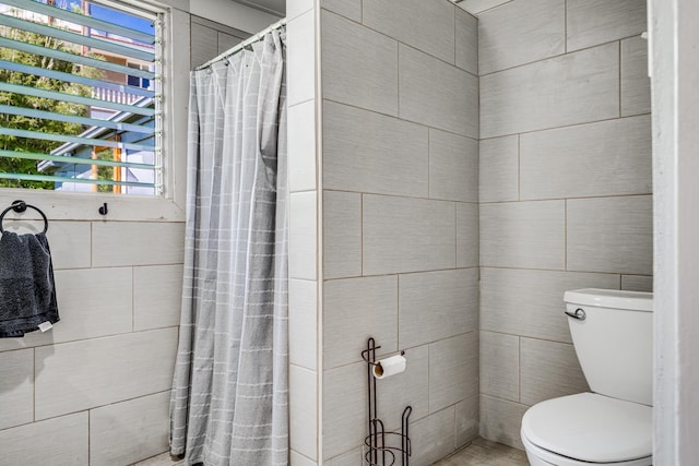 bathroom with tile walls, toilet, and a shower with curtain