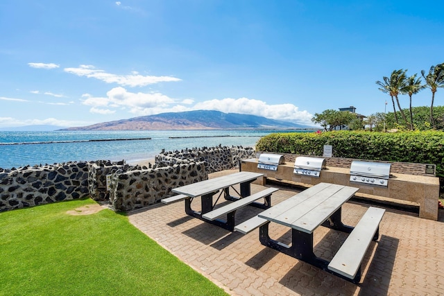 view of patio with exterior kitchen, grilling area, and a water and mountain view